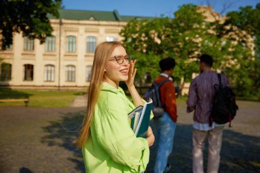 Genç ve güzel kız öğrencinin mutlu olduğu bir yan manzara portresi. Neşeli bir şekilde gülümseyen güzel okullu kız