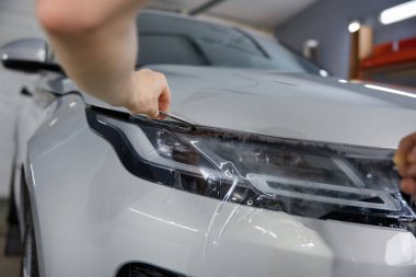 İşçi temizleyicisi polimer koruyucu dış kaplamayı kesiyor. Araba servisi şefinin yakın çekimi.