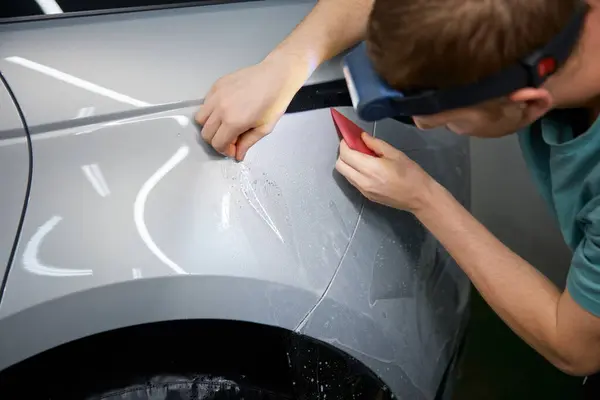 汽车服务站用橡胶刮板在汽车上粘贴保护膜的闭塞主控手 — 图库照片