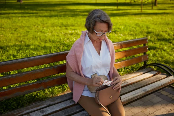 老太太在公园里散步时感到不舒服 就从包里吃药 老年人健康问题概念 — 图库照片