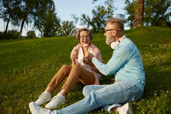 stock image Happy joyful senior couple eating ice-cream in park. Elderly married man and woman fooling around making jokes having snack during walk