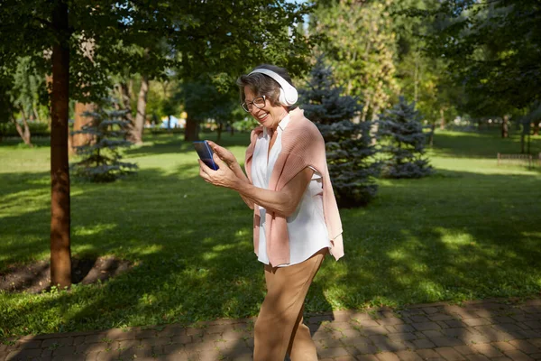 Starsza Kobieta Zestawie Słuchawkowym Wideo Rozmowy Online Smartfonie Pomocą Bezprzewodowego — Zdjęcie stockowe