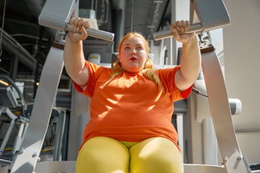 Spor malzemeleriyle spor salonunda ağır nefes alan terli obez kadın. Zayıflama ve sağlık hizmeti kavramı
