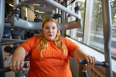 Spor malzemeleriyle spor salonunda ağır nefes alan terli obez kadın. Zayıflama ve sağlık hizmeti kavramı