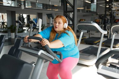 Spor salonunda antrenman yaparken koşu bandında obezite geçiren yorgun genç bir kadın. Umutsuzluk, yorgunluk, motivasyon ve tükenmişlik kaybı