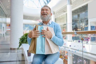 Alışveriş merkezinde alışverişi olan mutlu moda yaşlı adam.