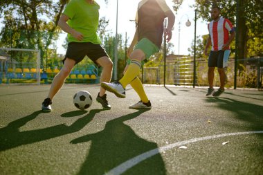 Şehir futbol sahasında top oynayan kendinden emin futbolcular. Erkek en iyi arkadaşlar aktif eğlence ve ortak hobi