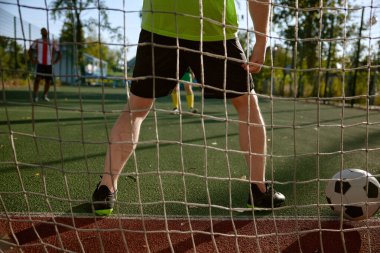 Futbol müsabakası sırasında futbol kapısında duran yakın kaleci. Sporcu gol atmayı engelliyor.