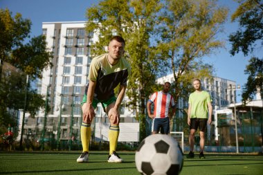 Düşünceli futbolcu penaltı golü atmaya çalışıyor. Şehir stadyumunda futbol oynayan arkadaşlar.