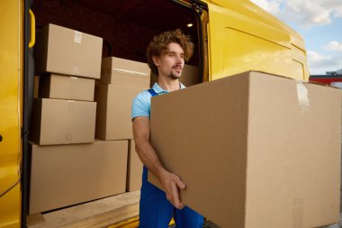 İş portresindeki erkek kurye. Teslimatçı karavanı paketlerle boşaltıyor. Depo ve mağaza nakliye malları servisi