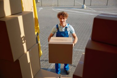 Üniformalı bir depo işçisi karavan yüklüyor teslimat için paket kutusu hazırlıyor. Müşteri siparişi ücretsiz olan çevrimiçi ürün alışveriş servisi