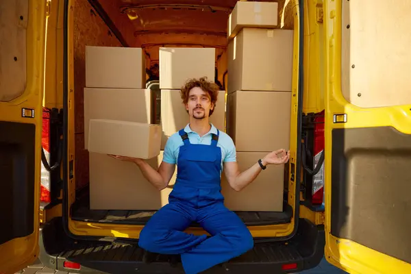 Courier meditating to keep calm mind holding parcel box in hand while sitting inside delivery truck