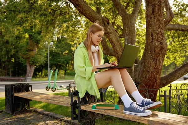 屋外でラップトップコンピュータを使用して研究仕事をしているティーンエイジャーガールの学生 ポジティブ 女子生徒 テキスト メッセージ または クラスのための要約 — ストック写真