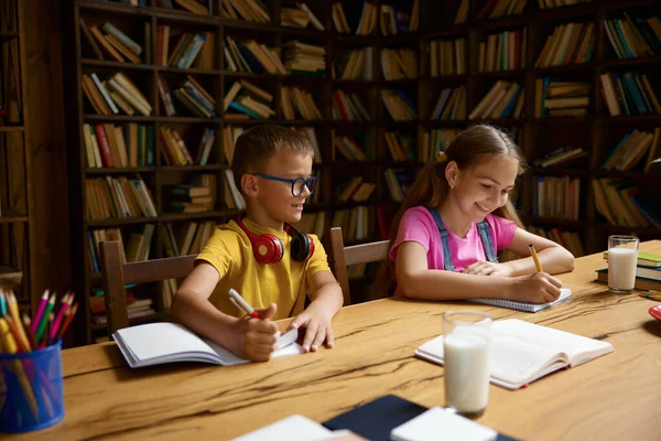 スマートな小さな兄弟姉妹は 自宅で一緒に宿題をしている間 コピーブックで執筆を勉強しています ホームスクーリング 遠隔教育コンセプト — ストック写真