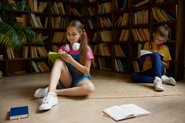 小学生は家図書館で時間を過ごしている 兄弟姉妹が宿題をする 教育の日に休憩中に素敵な休暇を持っている — ストック写真