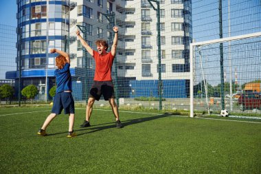 Heyecanlı baba ve oğul, zaferi kutlayan futbol maçını kazandıkları için seviniyorlar. Neşeli baba ve çocuk beşlik çakıyor başarılı futbol antrenmanları ve eğlenceli oyunlarla birbirlerini kutluyorlar.