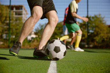 Futbolcu topa vuruyor. Şehir stadyumundaki arkadaşlar arasındaki amatör futbol maçı.