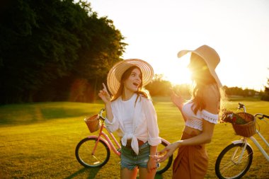 Yaz akşamları parkta gün batımının keyfini çıkaran iki sıradan genç kadın. Bisikletle seyahat eden genç bayan bisikletçi.