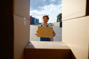 Depo çalışanı elinde dosya kutusu olan bir teslimat kamyonu boşaltıyor. Envanter yönetimi ve sevkiyat servisi