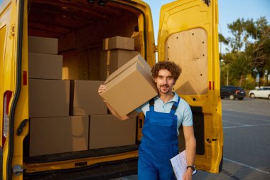 Teslimatçı elinde satın alınmış eşyalarla birlikte karton kutular taşıyor. Müşteri konseptine paket gönderimi