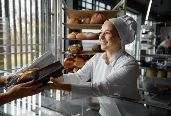 Venlig Smilende Sælger Bageri Passerer Brød Til Kunden Skranken Friske - Stock-foto