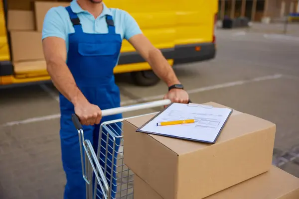 Professional delivery and parcels shipping service concept. Closeup trolley cart with cardboard box stack and clipboard checklist