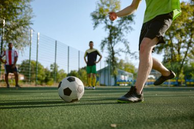 Bir grup genç erkek arkadaş yaz günü dışarıda futbol oynuyorlar. Spor antrenmanı dışarıda.