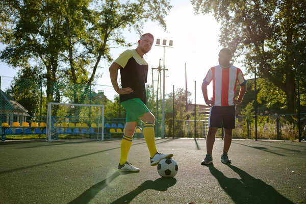 Two sportsmen in sportive wear with soccer ball standing on field preparing to play football. Weekend workout, training class for aduts