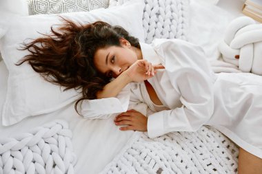 Yatakta yatan şehvetli, baştan çıkarıcı, genç bir kadın. Kadın cazibesi, saflık ve masumiyet kavramı.