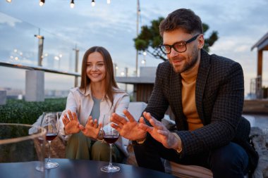 Genç ve rahat romantik çift çatıda buluşurken dekoratif şöminenin önünde ellerini ısıtıyorlar. Erkek arkadaş ve kız arkadaş şarap içip eğleniyorlar.