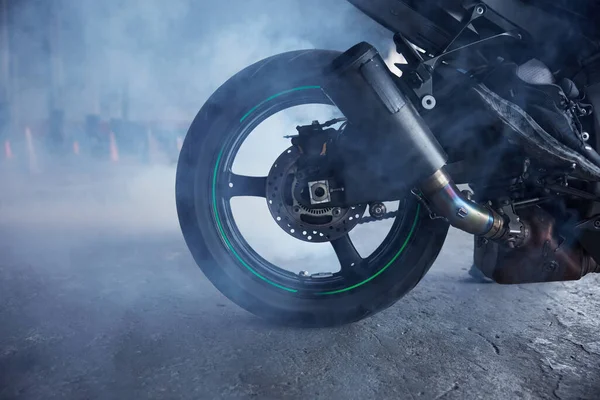 Closeup motorbike wheel over training track of driving school in smoke. Speed riding practice for biker beginner