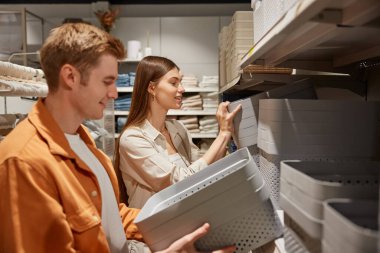 Genç evli çift plastik ev kutuları alıyor. Süpermarkette aile günlerinin tadını çıkarıyorlar.