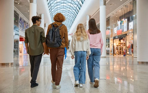 Bir grup genç arkadaş şehir merkezindeki büyük mağazadan alışveriş yapıyor. Genç sınıf arkadaşları eğlence ve eğlence için yürüyorlar ve indirimli kara cuma indirimi yapıyorlar.