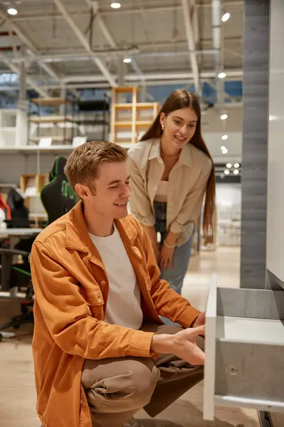 Mutlu genç aile evi dekore etmek için yeni mobilyalar seçiyor. Millennial erkek ve kadın hafta sonları perakende pazarından mutfak dolabı alıyorlar.