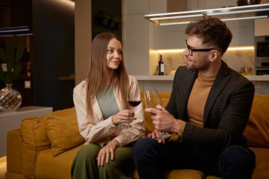 Evde romantik bir akşam erkek ve kadının ellerinde kırmızı şarap kadehleri tokuşturuyor. Mutlu genç çift evde huzurlu bir atmosferin keyfini çıkarıyor, hafta sonlarını kutluyorlar.