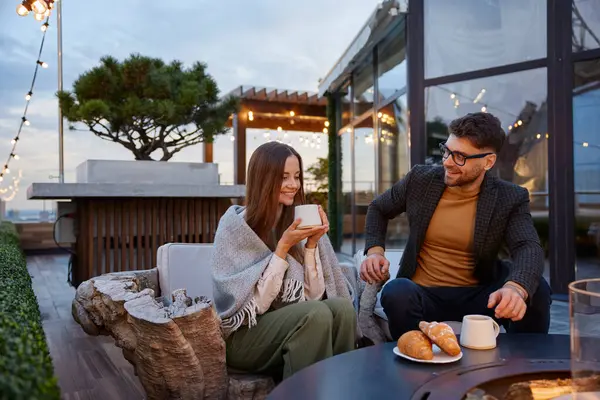 Young couple engaged in friendly conversation and drinking coffee. Lovers spending time together sitting on top of building drinking wine