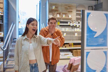 Modern mobilya mağazasında indirimli fiyatlar ve indirimler görünce sevinen genç bir çift. Satılık alışveriş, Kara Cuma veya Noel toptan satış konsepti