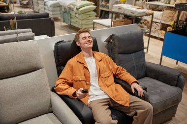 Rahat deri koltukta oturan rahat bir adam huzur ve stres olmadan modern mobilya perakende pazarında alışveriş yapmanın tadını çıkarıyor.