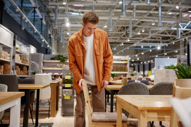 Markette dolap seçen genç bir adam. Mobilya alışverişi.