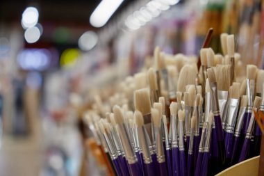 Kırtasiyede resim çizmek için boya fırçasıyla seçici bir odak. Sanatçı, yaratıcı stüdyo ve sanat sınıfı için sanatsal boya fırçaları