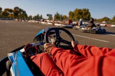 Yakın çekimde go-kart yarışçısı direksiyona odaklanmış bir şekilde spor araba kullanıyor. Eğlence amaçlı takip, hız yarışları konsepti