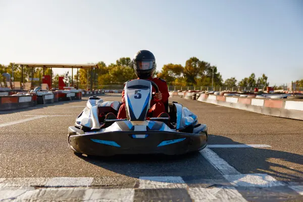 Competitive man racing in go-carts at finish of motor race track. Open air speed automotive competition