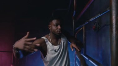 Havalı bir gece kulübünün neon ışıklarında dans eden moda kaslı rapçisi. Modern hip-hop dansçısı serbest dans gösterisi yapıyor.