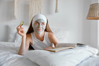 Gülümseyen genç bir kadının portresi, spa ameliyatının keyfini çıkarıyor. Milenyum dişisi cilt bakımı için balçık maskesi ve salatalık göz bandı takıyor. Güzellik tedavi konsepti