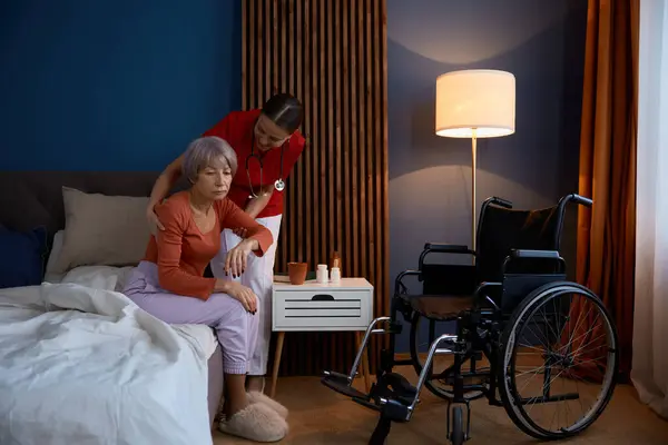 긍정적 간병인 침실에서 불행한 노인을 침대에서 휠체어로 이동하는 장애를 환자를 — 스톡 사진