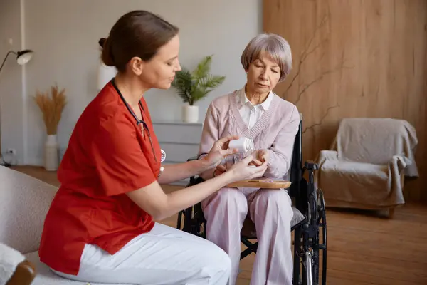 女性看護師の介護者は 医療支援のために老婆に錠剤を投与する 老人ホームコンセプトにおける高齢者のための医療支援 退職医療保険 — ストック写真