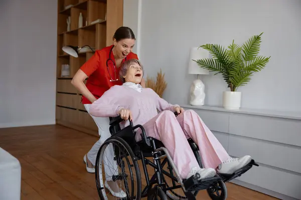 간병인 휠체어에 환자를 놀라운 양육권 가정에서 노인과 시간을 즐기는 유머스러운 — 스톡 사진