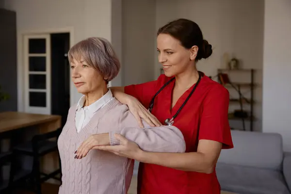 女性のリハビリテーションセラピストは 家庭や退職後の家で上級女性の運動を支援します 身体的問題や障害のある高齢者のための専門医療サービス ストック画像