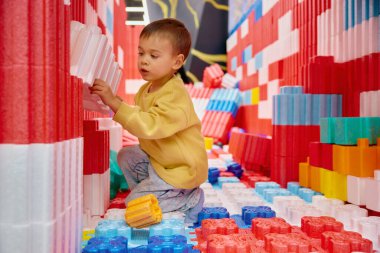 Çocuk eğlence merkezinde büyük yapı taşlarıyla oynuyor. Çocuk parkındaki çocuklar için güvenli yumuşak renkli şantiye