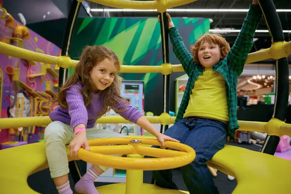Happy excited children playing on indoor carousel at play center. Weekend activity enjoyment and amusement childhood